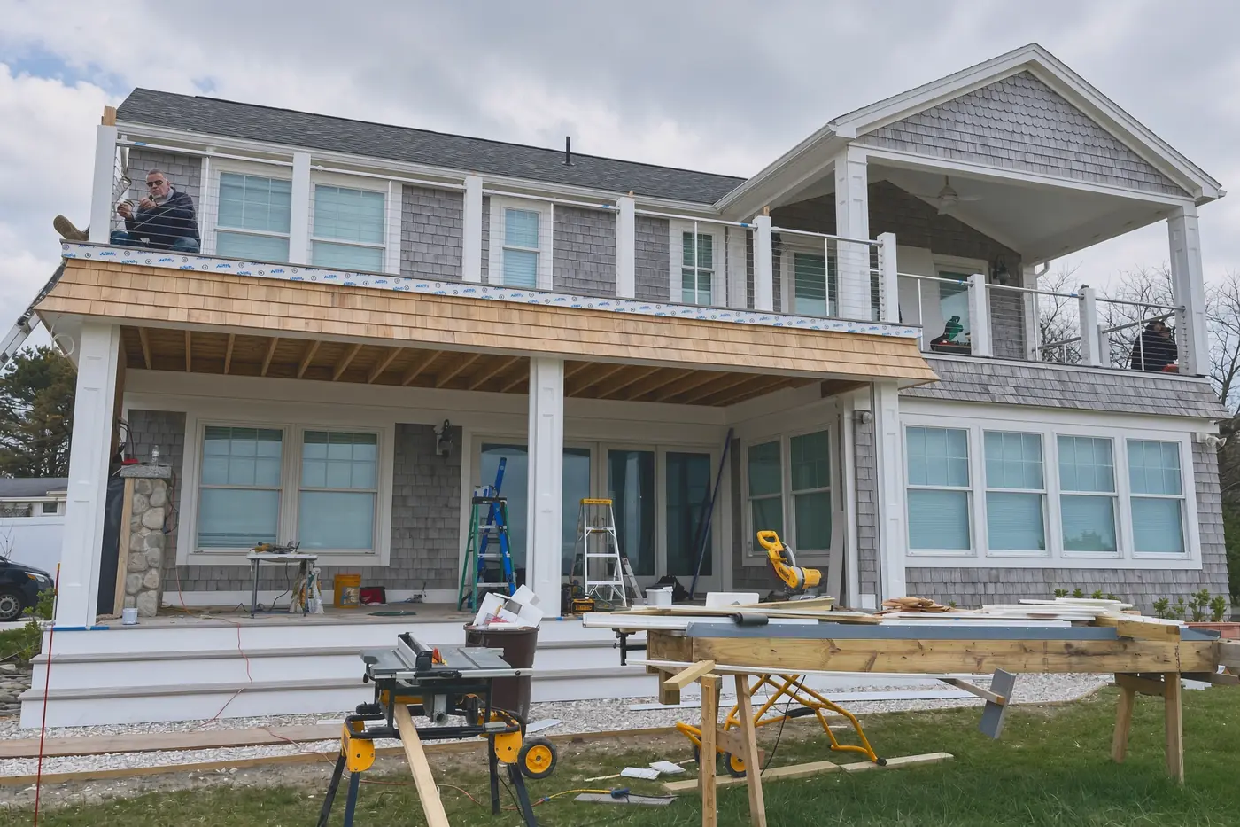 Covered porch and second-floor deck under construction with cable rail