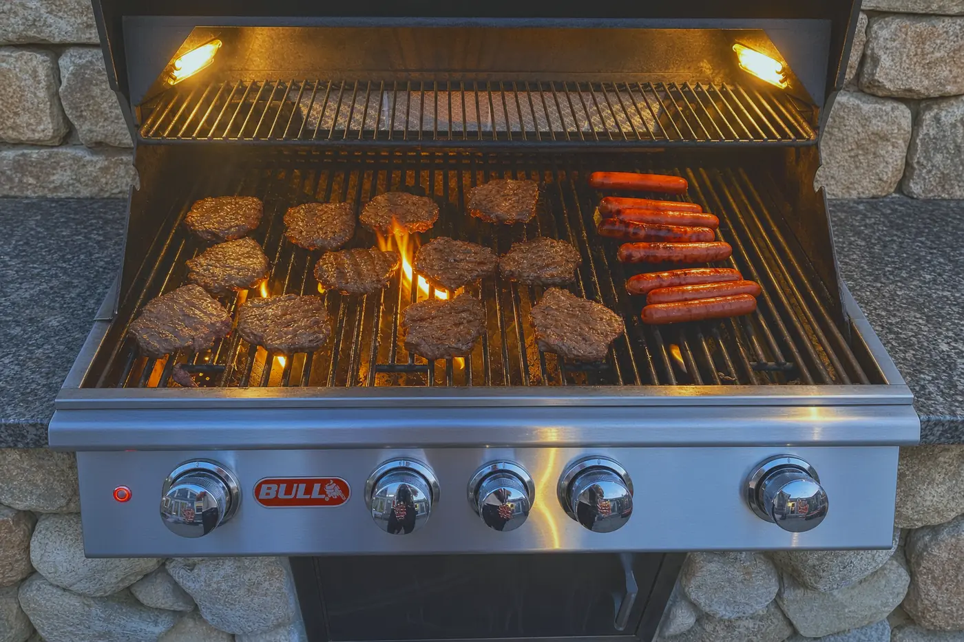 Built-in gas grill set into a stone counter, running at dusk