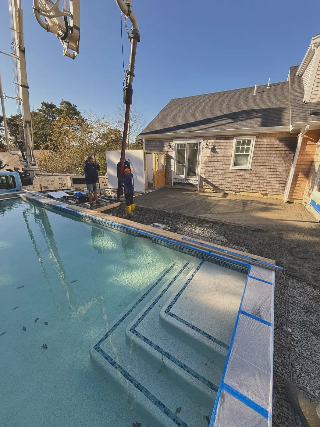 Concrete pump placing a pool patio slab over wire mesh